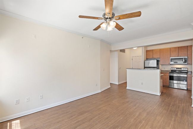 Unfurnished living room featuring crown molding, light wood finished floors, and ceiling fan | Image 8