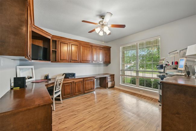 Office space featuring built in study area, a ceiling fan, and light wood finished floors | Image 11
