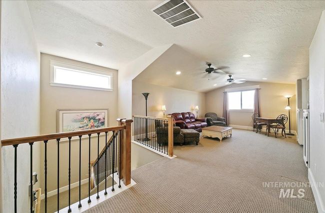Carpeted living room featuring lofted ceiling, a textured ceiling, and a ceiling fan | Image 30