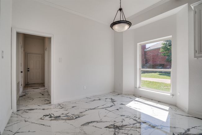 Empty room with light marble finish floors, crown molding, and baseboards | Image 9