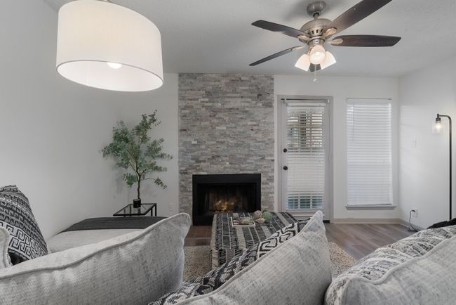 Living room with a fireplace, wood finished floors, a ceiling fan, and baseboards | Image 9