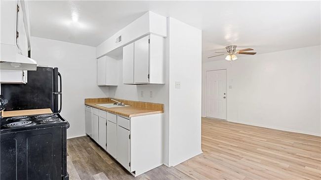 Kitchen featuring sink, white cabinetry, light hardwood / wood-style flooring, ceiling fan, and black appliances | Image 24