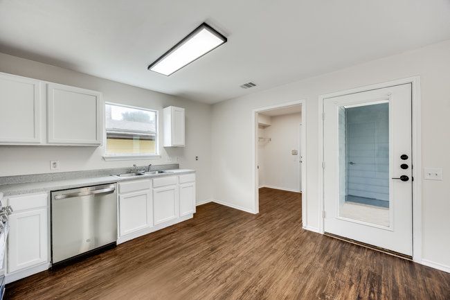 Kitchen featuring dishwasher, a sink, white cabinets, light countertops, and dark wood-style flooring | Image 18