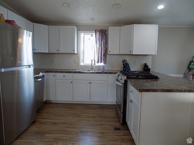 Kitchen featuring sink, hardwood / wood-style flooring, white cabinets, and appliances with stainless steel finishes | Image 5