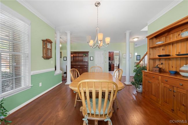 Dining area featuring ornate columns, a chandelier, dark wood-style flooring, and ornamental molding | Image 11