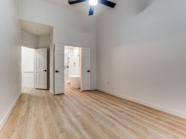 Unfurnished bedroom featuring light wood-style flooring, connected bathroom, a high ceiling, and ceiling fan | Image 16