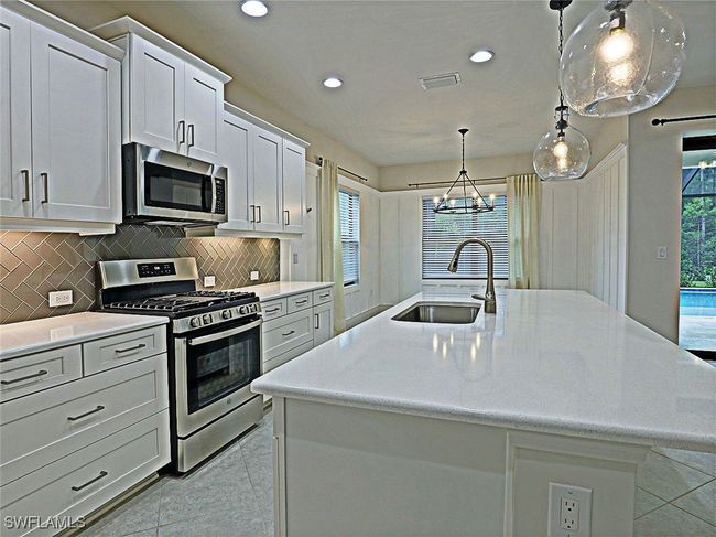 Kitchen featuring appliances with stainless steel finishes, a sink, a kitchen island with sink, backsplash, and recessed lighting | Image 9
