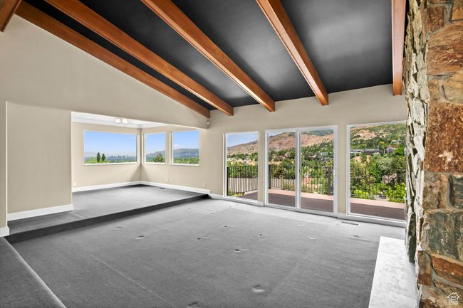 Unfurnished living room with beam ceiling, plenty of natural light, carpet flooring, and high vaulted ceiling | Image 12