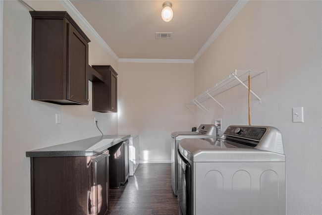 This laundry room boasts a modern washing machine and ample cabinetry for all your storage needs. | Image 19