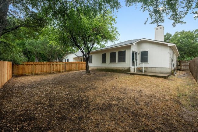 Back of property with a flat yard and a fenced backyard with new fence on two sides. | Image 22