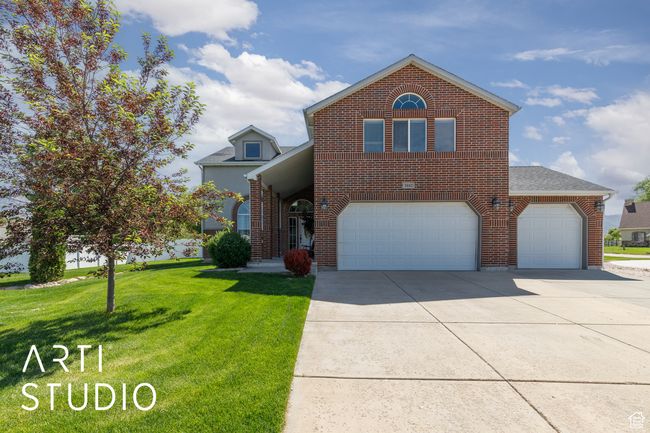 Traditional home featuring brick siding, concrete driveway, a front lawn, an attached garage, and roof with shingles | Image 5