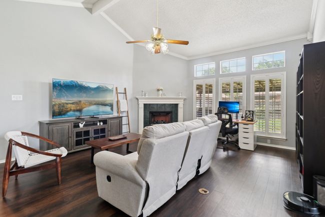Living room with an office area, ceiling fan, a tile fireplace, dark wood-type flooring, and baseboards | Image 5