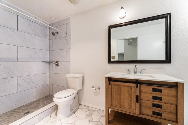 Bathroom with toilet, a textured ceiling, a tile shower, and vanity | Image 10