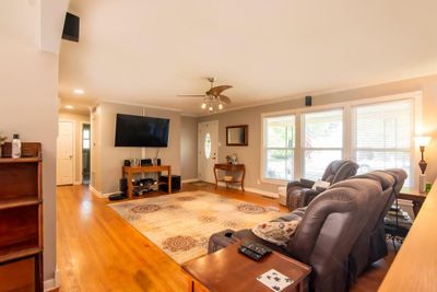 Living room with crown molding, light hardwood / wood-style flooring, and ceiling fan | Image 2