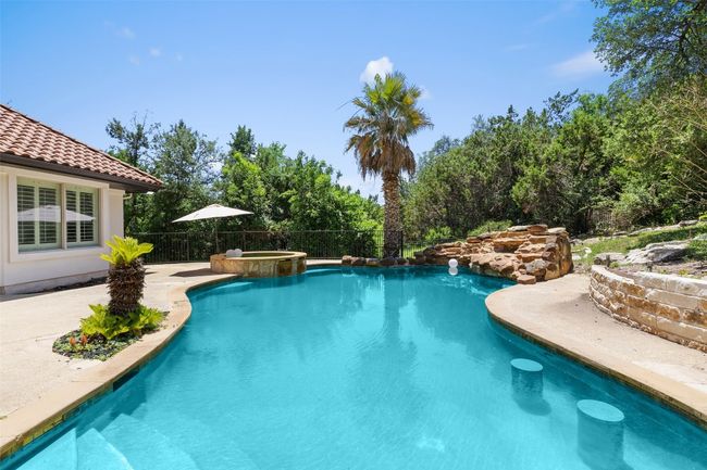 View of swimming pool with a pool with connected hot tub, fence, and a patio | Image 37