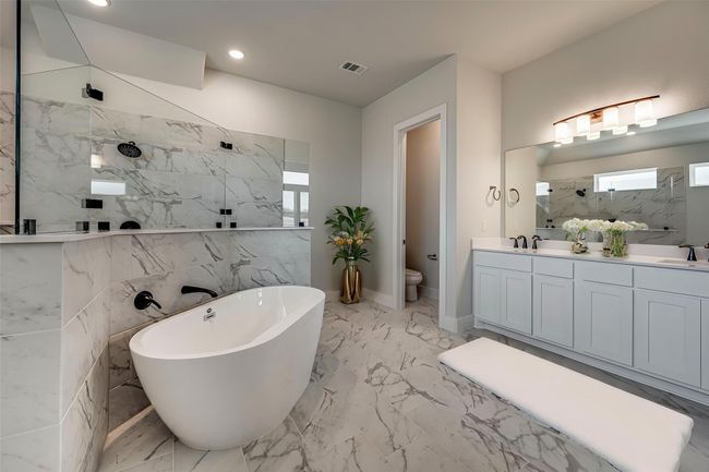 Full bathroom with a freestanding tub, walk in shower, toilet, marble finish floor, and a sink | Image 12
