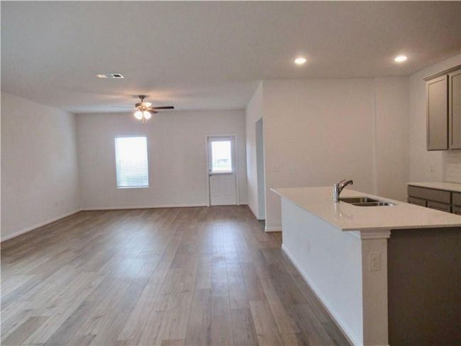 Kitchen with light countertops, a center island with sink, a ceiling fan, wood finished floors, and recessed lighting | Image 6
