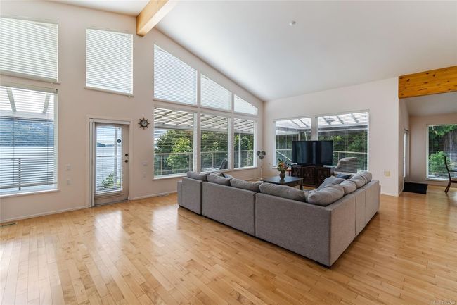 Living area featuring beam ceiling, light wood-type flooring, plenty of natural light, high vaulted ceiling, and baseboards | Image 24
