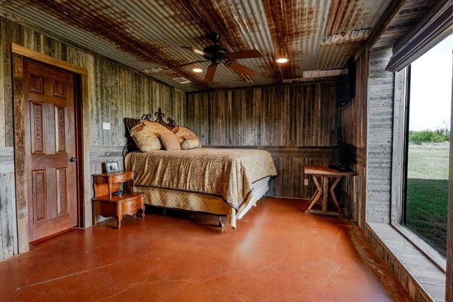 Bedroom featuring concrete floors, wood walls, and access to outside | Image 23