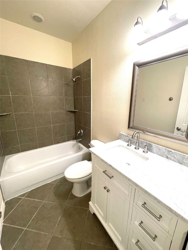 Bathroom featuring vanity, shower combination, tile patterned flooring, and a textured wall | Image 16