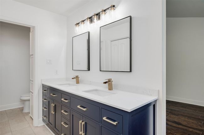 Bathroom featuring a sink, double vanity, toilet, and baseboards | Image 25