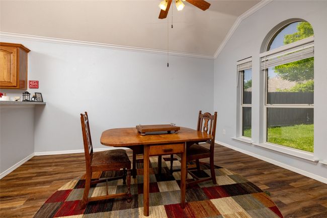 Dining area with lofted ceiling, dark wood finished floors, ceiling fan, and crown molding | Image 12