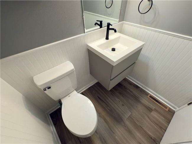 Bathroom with vanity, toilet, a wainscoted wall, visible vents, and wood finished floors | Image 8