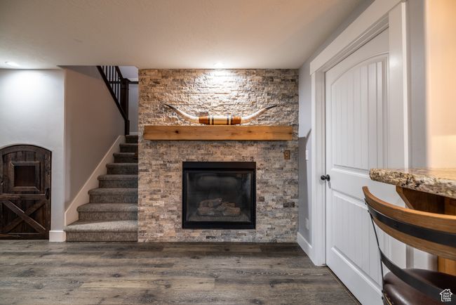Living room featuring a stone fireplace, wood finished floors, stairway, and recessed lighting | Image 48