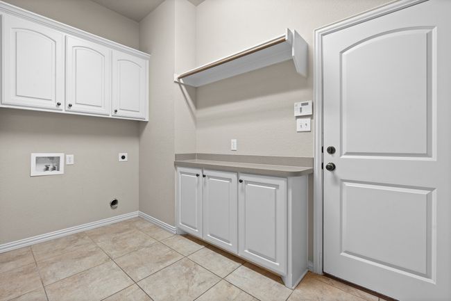 Washroom featuring hookup for an electric dryer, hookup for a washing machine, cabinet space, and light tile patterned floors | Image 26