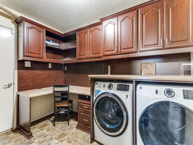 Washroom with separate washer and dryer, cabinet space, an office area, and a textured ceiling | Image 7