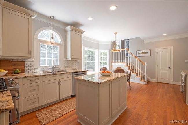 Kitchen featuring crown molding, decorative backsplash, stainless steel appliances, a sink, and hanging light fixtures | Image 15