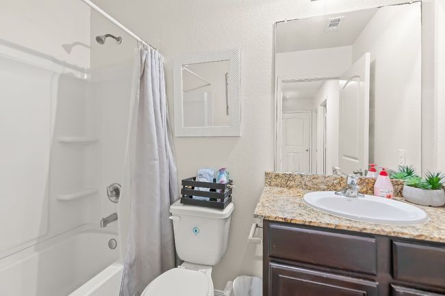 Full bathroom with toilet, vanity, and shower / bathtub combination with curtain | Image 16