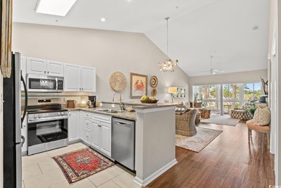 Kitchen with light stone counters, stainless steel appliances, white cabinetry, sink, and kitchen peninsula | Image 2