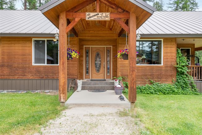 View of exterior entry featuring a standing seam roof, a metal roof, and a yard | Image 21