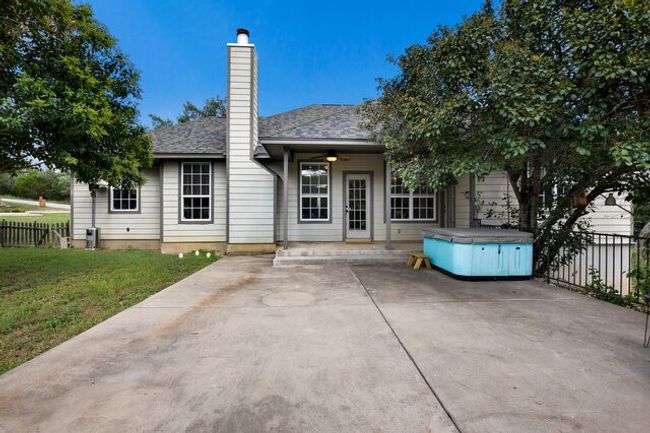 Rear view of property with a chimney, a hot tub, ceiling fan, and a patio area | Image 31