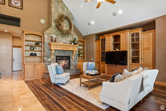 Living area featuring high vaulted ceiling, ceiling fan, a stone fireplace, arched walkways, and baseboards | Image 25