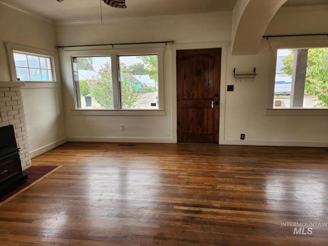 Entrance foyer with dark wood-type flooring, ornamental molding, ceiling fan, and a brick fireplace | Image 4