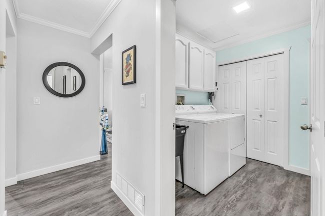 Washroom featuring independent washer and dryer, ornamental molding, visible vents, wood finished floors, and cabinet space | Image 22