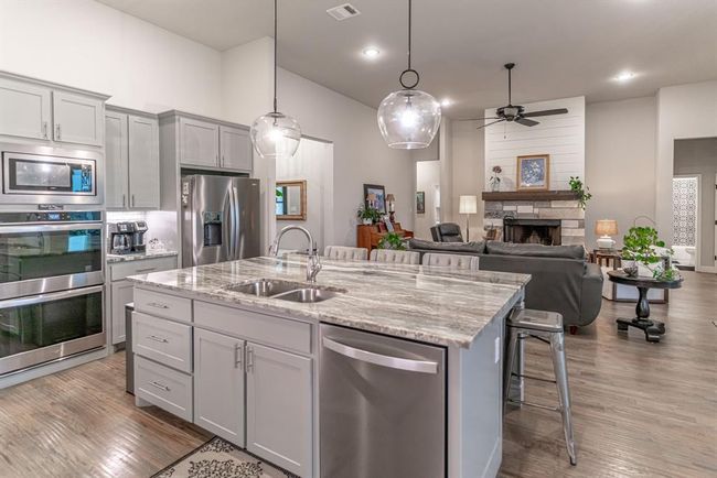 Kitchen with light hardwood / wood-style flooring, tasteful backsplash, stainless steel appliances, gray cabinets, and light stone counters | Image 11