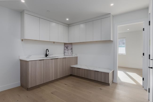 Kitchen with modern cabinets, a sink, recessed lighting, light wood finished floors, and baseboards | Image 18