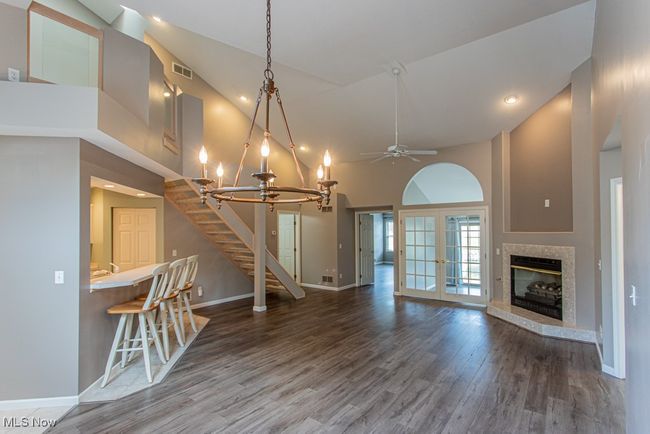 Unfurnished living room with a chandelier, stairway, a premium fireplace, wood finished floors, and a ceiling fan | Image 19