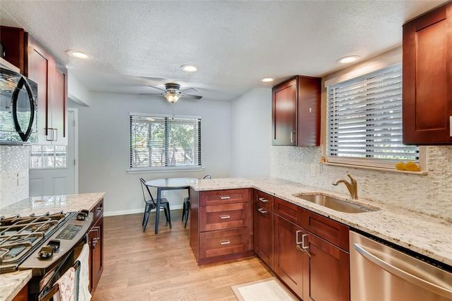 Kitchen with stainless steel dishwasher, a sink, gas stove, light wood-type flooring, and black microwave | Image 9