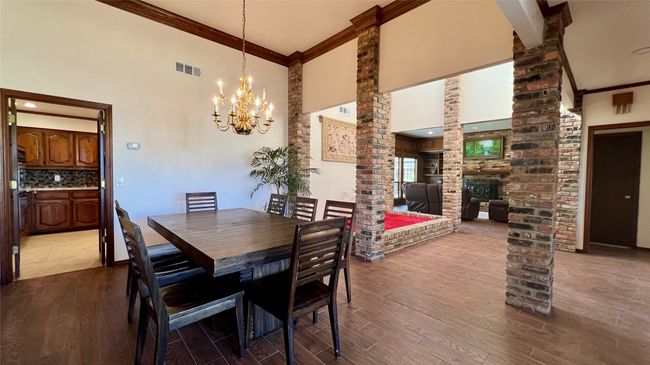 Dining space with ornate columns, high vaulted ceiling, dark wood-style floors, a chandelier, and ornamental molding | Image 5