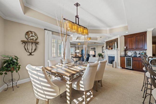 Dining area featuring a tray ceiling, ornamental molding, light carpet, wine cooler, and recessed lighting | Image 15