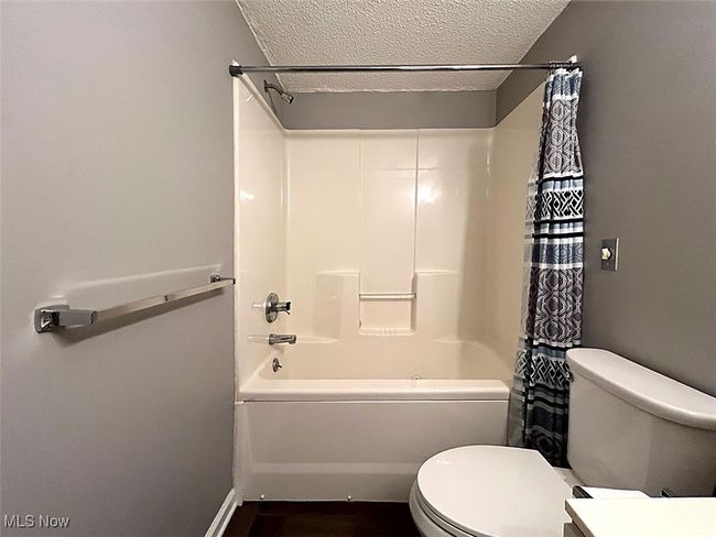 Laundry/full bathroom featuring shower / bath combination with curtain, a textured ceiling, wood finished floors, and vanity | Image 20