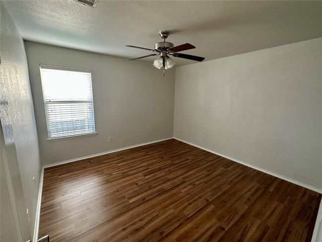 Empty room featuring baseboards, a textured ceiling, ceiling fan, and dark wood-style flooring | Image 11