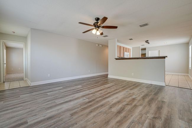 Unfurnished living room featuring a ceiling fan and light wood-style flooring | Image 12