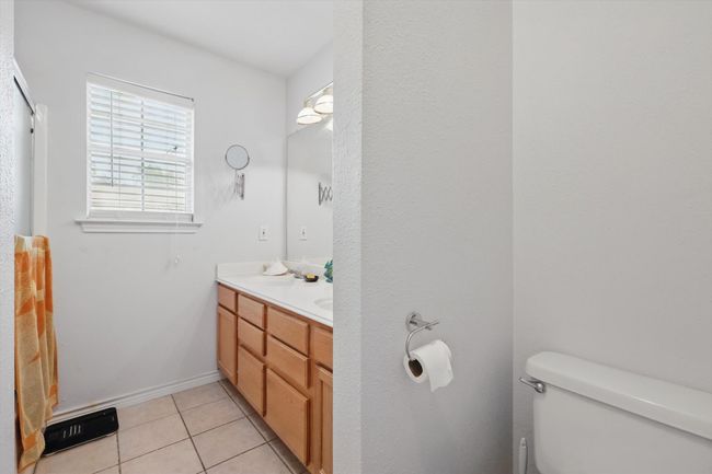 Bathroom with baseboards, double vanity, tile patterned flooring, toilet, and a sink | Image 22