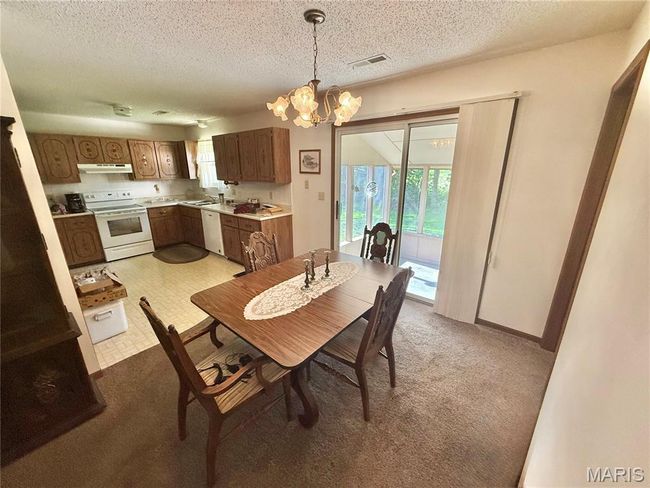 Dining room featuring a chandelier, light carpet, and a textured ceiling | Image 22