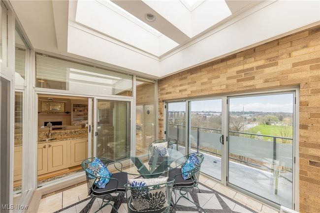 Sunroom featuring tile flooring, a skylight, outdoor dining area, sliders to balcony | Image 20